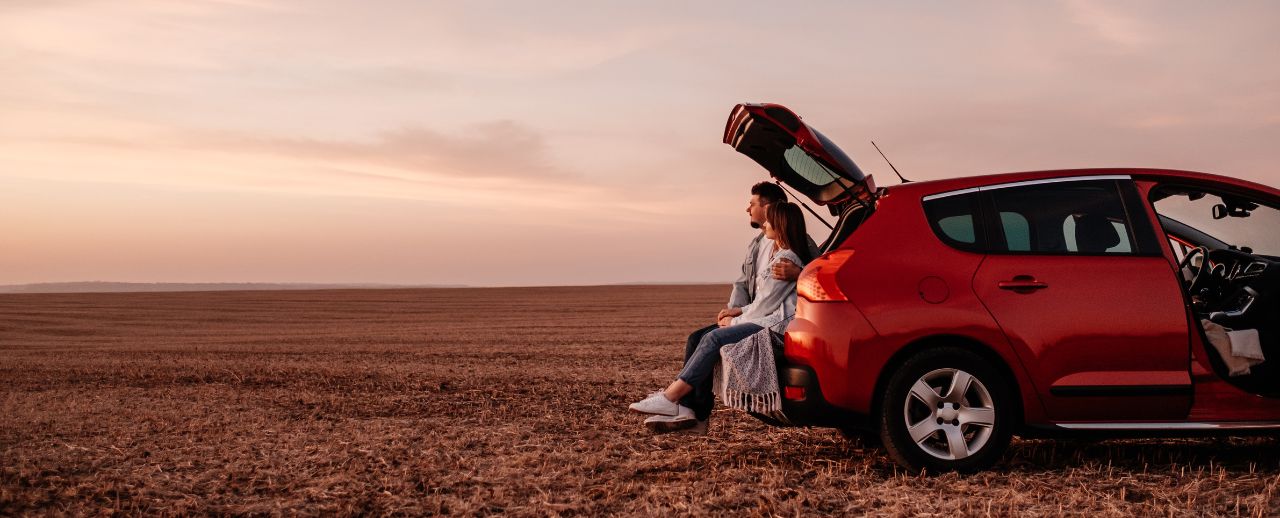 Pareja junto a su coche disfrutando del viaje
